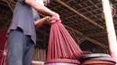Perajin mengecat hio ketika proses pembuatan di kawasan Tangerang, Banten, Kamis (28/1/2021). Menjelang Imlek atau Tahun Baru China, permintaan akan Hio terus mengalami peningkatan untuk kebutuhan sembahyang warga keturunan Tionghoa. (Liputan6.com/Angga Yuniar)