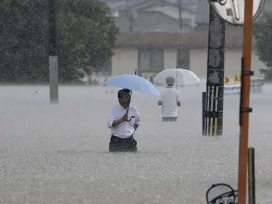 Orang-orang menyeberang jalan akibat hujan lebat di Kurume, Prefektur Fukuoka, Jepang selatan Senin, 10 Juli 2023. (Kyodo News via AP)