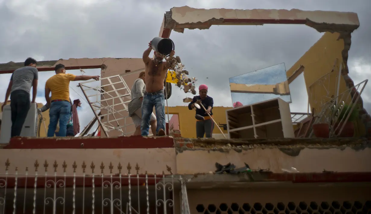 Sejumlah warga membersihkan puing-puing di sebuah bangunan setelah badai tornado menghantam Regla, Kuba (28/1). Akibat bencana tersebut tiga orang tewas dan 173 orang lainnya luka-luka. (AP Photo/Ramon Espinosa)