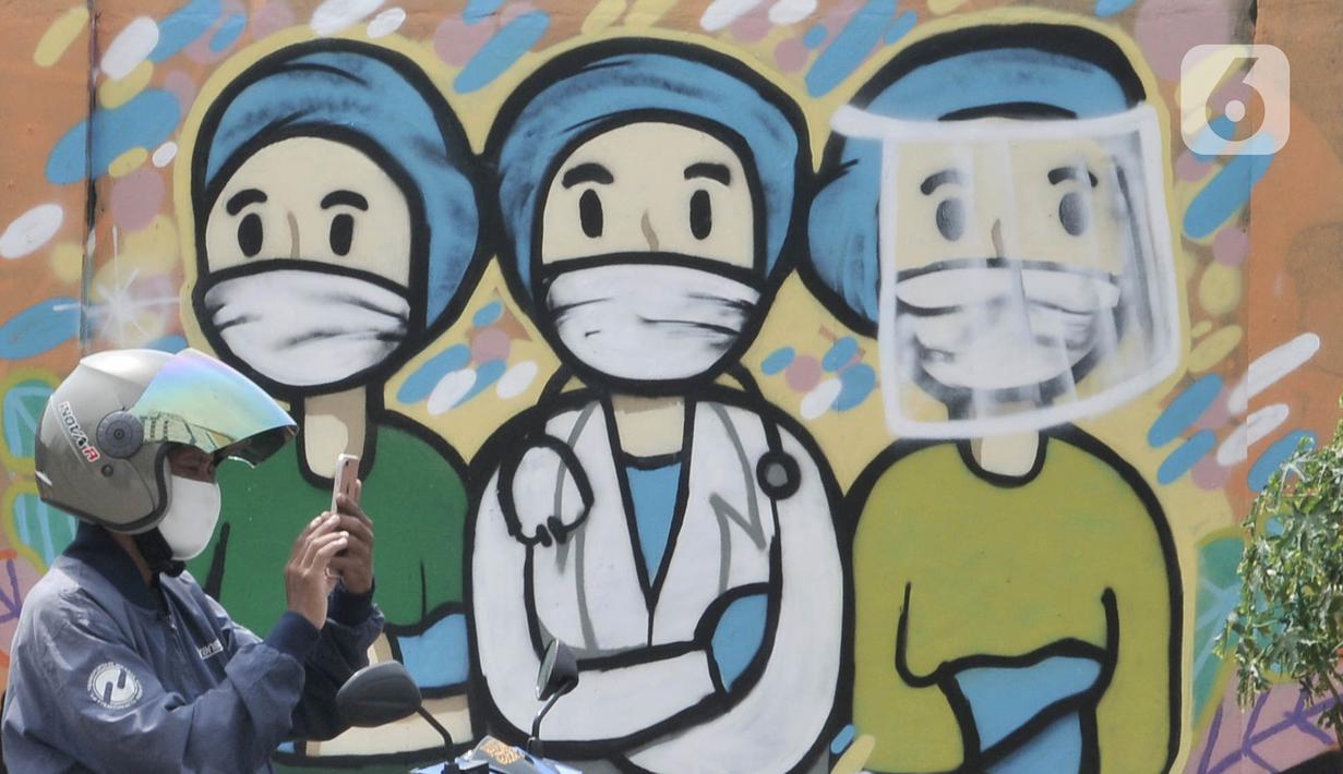 Pengendara melintas di depan mural dukungan untuk tim medis Covid-19 di kawasan Sunter, Jakarta, Rabu (27/5/2020). Mural tersebut sebagai bentuk dukungan untuk tim medis penanganan Covid-19 sekaligus mengingatkan masyarakat agar taat mengikuti aturan PSBB. (merdeka.com/Iqbal S. Nugroho)
