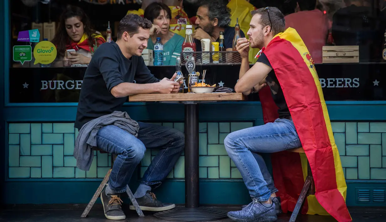 Dua pria berada di sebuah restoran di pusat kota Barcelona setelah demonstrasi menentang deklarasi kemerdekaan Catalonia, di Barcelona, Spanyol, (29/10). Mereka menyerukan persatuan dan menolak deklarasi kemerdekaan Catalan. (AP Photo/Santi Palacios)