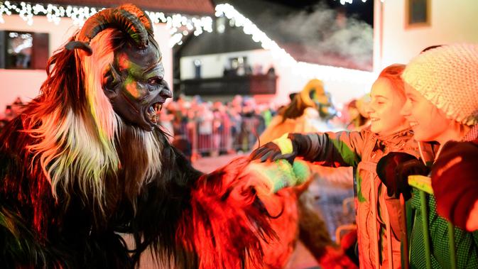 Anak-anak berbincang dengan partisipan berpakaian seperti Krampus, makhluk setengah iblis, dalam parade di Podkoren, Slovenia, Jumat (30/11). Tradisi natal ini juga dilakukan di beberapa negara seperti Austria, Jerman, Hungaria dan Ceko (Jure Makovec/AFP)