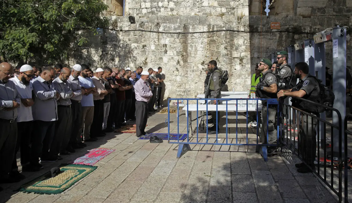 Petugas polisi perbatasan Israel berjaga-jaga saat umat muslim berdoa di luar komplek Masjid Al- Aqsa, Yerusalem, Minggu (16/7). Ratusan umat muslim mengunjungi tempat suci di Yerusalem setelah Israel membuka kembali tempat tersebut. (AP/Mahmoud Illean)