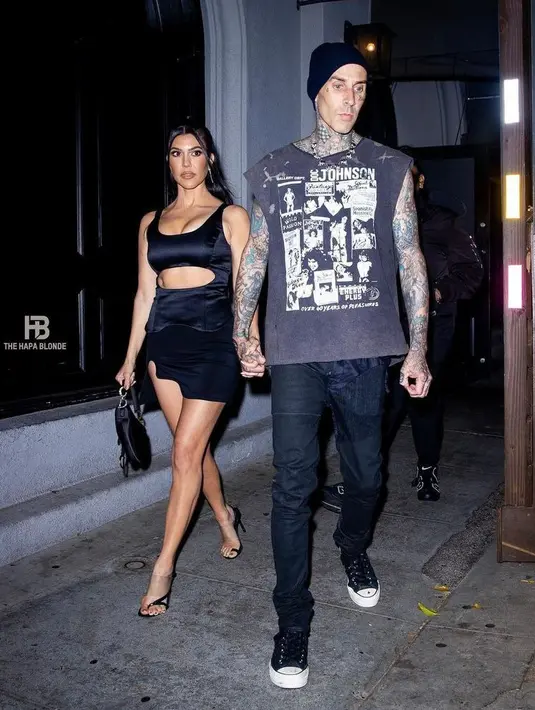 Kourtney tampil seksi dengan silk black dress dengan potongan di perut. Sementara gaya Travis lebih sederhana dengan balutan cutoff grafis t-shirt dan celana jeans hitam.(Instagram/kravis_love).