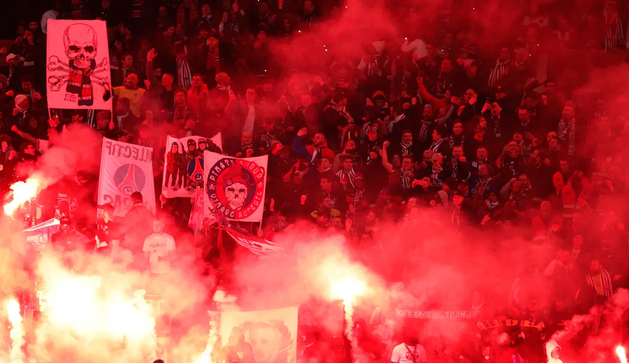 Para pendukung Paris Saint-Germain menyalakan suar sambil meneriakkan yel-yel dukungan saat pertandingan melawan Real Madrid di stadion Parc des Princes di Paris (6/3). (AP Photo / Francois Mori)