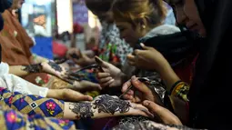 Sejumlah wanita Pakistan membuat henna dengan pacar di salon kecantikan menjelang Hari Raya Idul Fitri di Karachi (3/6/2019). Umat Muslim di seluruh dunia sedang bersiap untuk merayakan Hari Raya Idul Fitri, yang menandai akhir bulan puasa Ramadan. (AFP Photo/Asif Hassan)