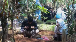 Warga datang bersama keluarga untuk mendoakan sanak saudara yang telah meninggal dunia. Tampak dalam foto, warga saat melakukan ziarah kubur usai melaksanakan salat Idulfitri 1447 Hijriah di salah satu Tempat Pemakaman Umum (TPU), Cibinong, Kabupaten Bogor, Jawa Barat, Sabtu (21/3/2026). (Kapanlagi.com/Budy Santoso)