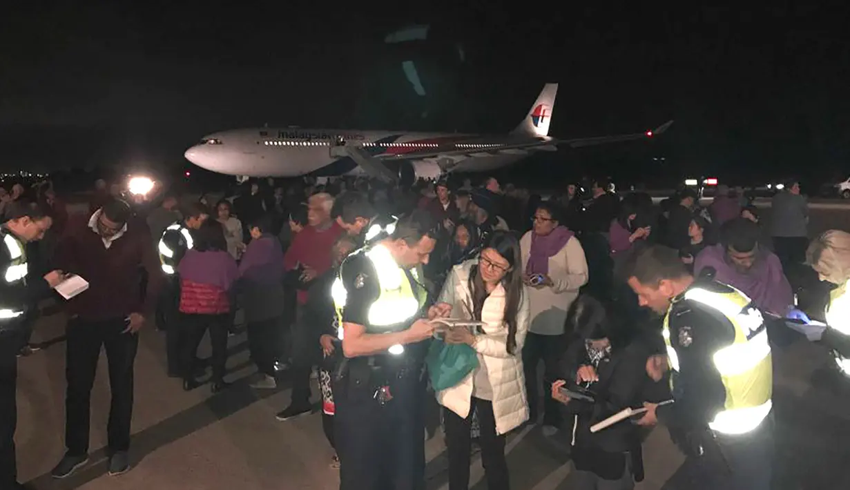 Foto yang mengambarkan situasi para penumpang berada di depan Malaysia Airlines Flight MH128 di Melbourne, Australia (1/6). Pesawat itu terpaksa kembali setelah seorang penumpang mengklaim memiliki bom dan memaksa masuk kokpit. (Andrew Leconcelli/AFP)