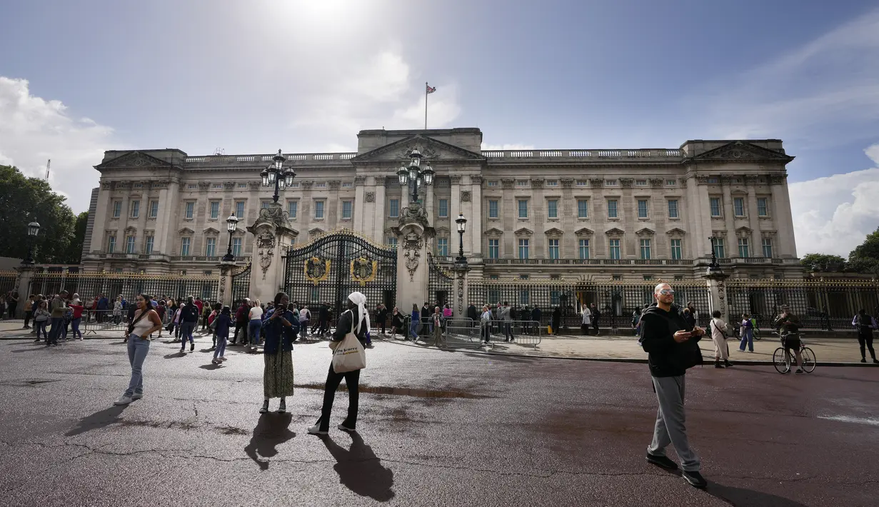 Turis berdiri di depan Istana Buckingham di London, Kamis (8/9/2022).  Istana Buckingham mengatakan Ratu Elizabeth II telah ditempatkan di bawah pengawasan medis karena dokter "memperhatikan kesehatan Yang Mulia." Anggota keluarga kerajaan pergi ke Skotlandia untuk bersama raja berusia 96 tahun itu. (AP Photo/Frank Augstein)