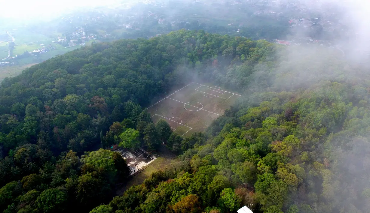 Saat fajar, kabut tebal menyelimuti lapangan sepak bola, namun berangsur-angsur hilang saat matahari terbit. (CLAUDIO CRUZ / AFP)