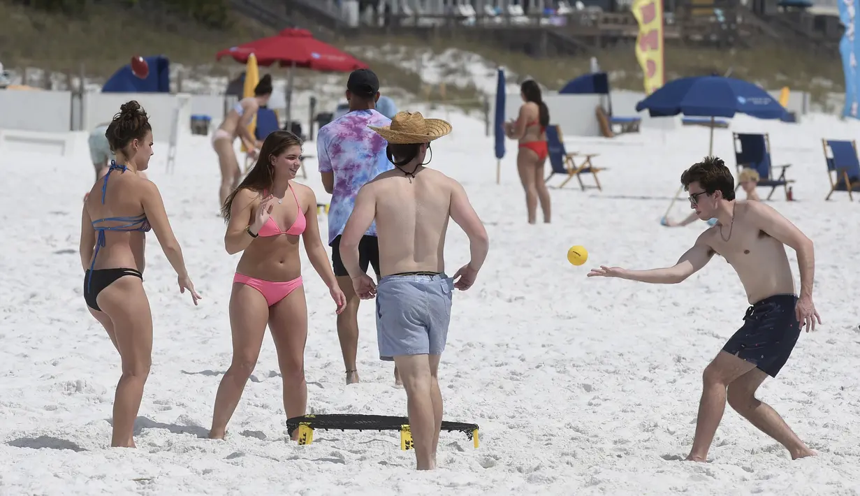 Para pengunjung pantai asyik bermain bola di Destin, Florida, Amerika Serikat, Rabu (18/3/2020). Virus corona COVID-19 sudah menyebar ke seluruh wilayah Amerika Serikat dengan jumlah kasus sebanyak 5.359 dan menewaskan 100 orang. (Devon Ravine/Northwest Florida Daily News via AP)