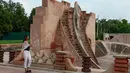 Pengunjung mengambil gambar saat melewati sebuah struktur di Jantar Mantar, New Delhi, 17 Juli 2018. Situs Jantar Mantar di New Delhi terdiri dari 13 instrumen utama untuk membuat perhitungan astronomi dan revisi kalender. (AFP/Sajjad HUSSAIN)