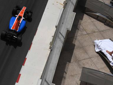 Pebalap Manor Racing, Pascal Wehrlein, melintas di dekat seorang turis yang sedang berjemur sambil menyaksikan latihan bebas F1 GP Monako di sirkuit jalan raya Monako. (AFP/Pascal Guyot)