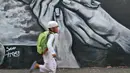 Seorang bocah berlari di depan dinding berhias mural bertema Islami di Gang Abdul Jabar, Jagakarsa, Jakarta, Senin (28/5). (Liputan6.com/Herman Zakharia)