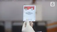Petugas menunjukkan surat pemungutan suara dalam pemilihan serentak 2020 saat simulasi di Halam Kantor KPU, Jakarta, Rabu (22/7/2020). Tahapan ini dilaksanakan dengan mengutamakan aspek kesehatan dan keselamatan bagi para pihak yang terlibat. (merdeka.com/Imam Buhori)