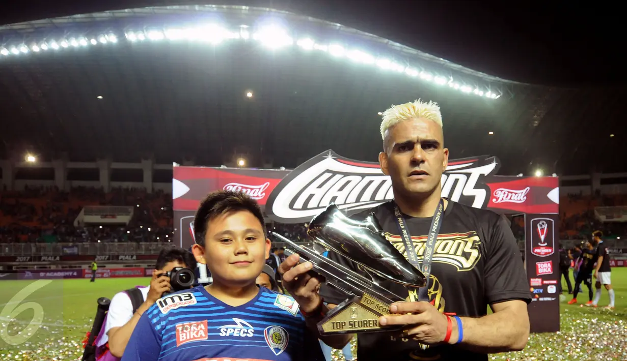Pemain Arema FC, Cristian Gonzales bersama putranya memamerkan trofi pencetak gol terbanyak Piala Presiden 2017 di Stadion Pakansari, Minggu (12/3). Cristian Gonzales meraih gelar pencetak gol terbanyak dengan 11 gol. (Liputan6.com/Helmi Fithriansyah)