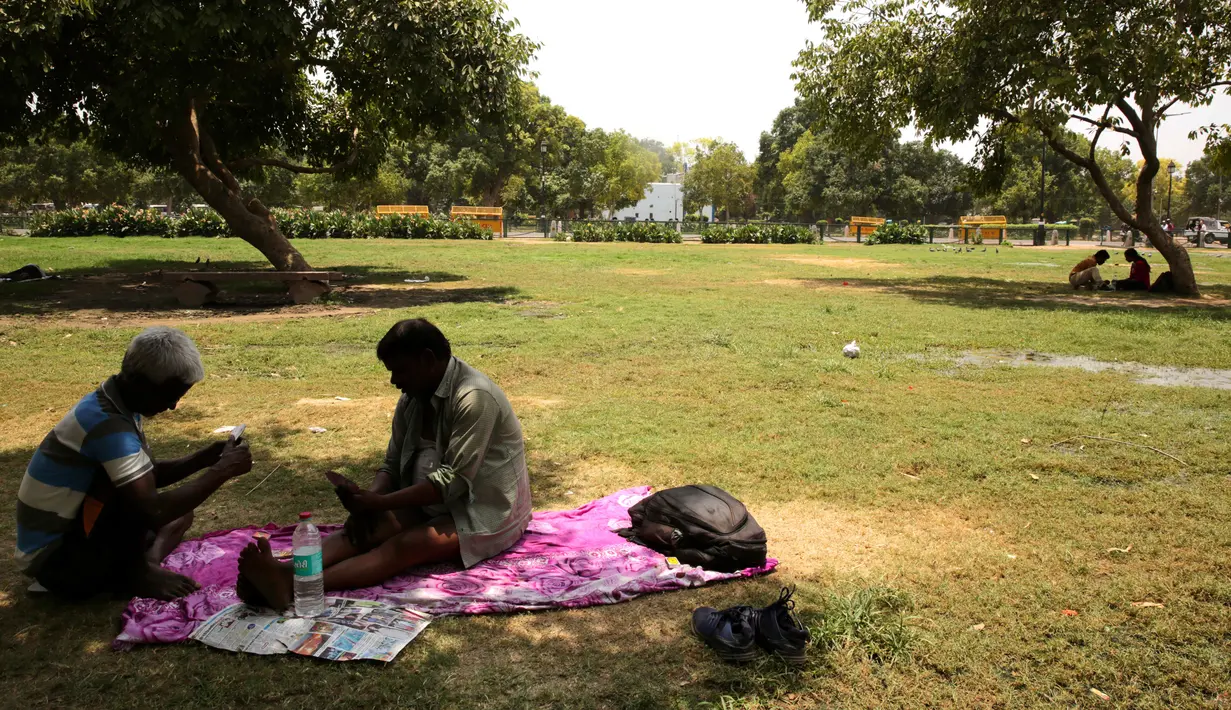 Warga duduk di bawah pohon selama musim panas di New Delhi, India (10/6/2019). Kondisi gelombang panas yang parah menyapu bagian utara dan barat India dengan suhu maksimum melonjak hingga 48 derajat Celcius ( 118 F) di beberapa bagian Rajasthan. (AP Photo/Manish Swarup)