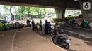 Pengendara motor beristirahat di jalur putar balik Jalan Gatot Soebroto, kawasan Kuningan, Jakarta, Selasa (12/11/2019). Jalur yang kini hanya bisa dilalui kendaraan roda dua itu menjadi lokasi sebagian pemotor beristirahat karena teduh tertutup jalan tol dalam kota. (Liputan6.com/Immanuel Antonius)