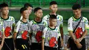 12 anak laki-laki dan pelatih sepak bola mereka, yang diselamatkan dari gua banjir di Thailand tampil ke muka publik untuk pertama kalinya di Chiang Rai, Rabu (18/7). Mereka memasuki ruang konferensi pers dengan memakai seragam. (AP/Vincent Thian)