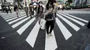 Orang-orang yang mengenakan masker pelindung untuk membantu mengekang penyebaran virus corona berjalan di tempat penyeberangan pejalan kaki di Tokyo (15/10/2020). Ibukota Jepang mengonfirmasi lebih dari 280 kasus virus korona baru pada hari Kamis. (AP Photo/Eugene Hoshiko)