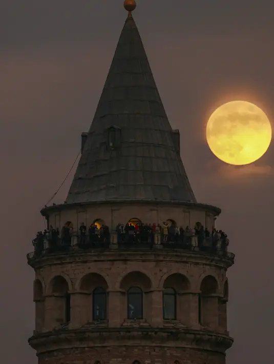 Bulan purnama terakhir tahun ini yang dikenal sebagai Cold Moon muncul di belakang menara Galata di Istanbul, Turki, Rabu (7/12/2022). Dijuluki Cold Moon karena Bulan purnama ini terbit pada salah satu malam “terpanjang” dalam setahun karena kedekatannya dengan titik balik Matahari musim dingin di Desember. (AP Photo/Emrah Gurel)