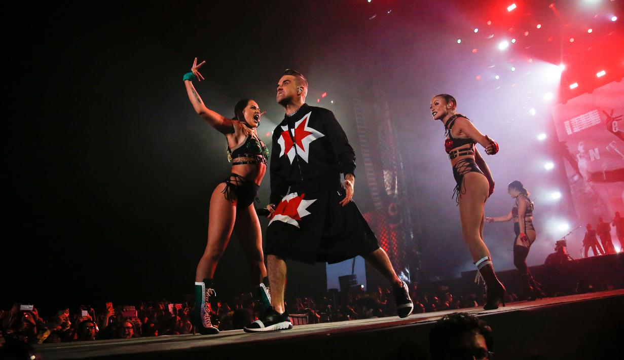 Aksi panggung Robbie Williams bersama para penari di Festival Musik Corona Capital di Meksiko (17/11). Pria 44 tahun ini tampil energik mengenakan setelan jas hitam dan rok yang dihiasi bintang merah. (AP Photo/Eduardo Verdugo)