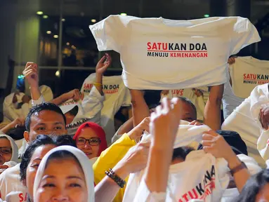 Pendukung Jokowi-Ma'ruf Amin mengangkat kaus pada acara Doa Bersama Lintas Agama dan Festival Seni Budaya di Jakarta, Jumat (12/4). Acara yang digelar Gerakan Alumni UI dan IKJ mengusung tema "SATUkan Doa menuju Kemenangan". (Liputan6.com/Angga Yuniar)