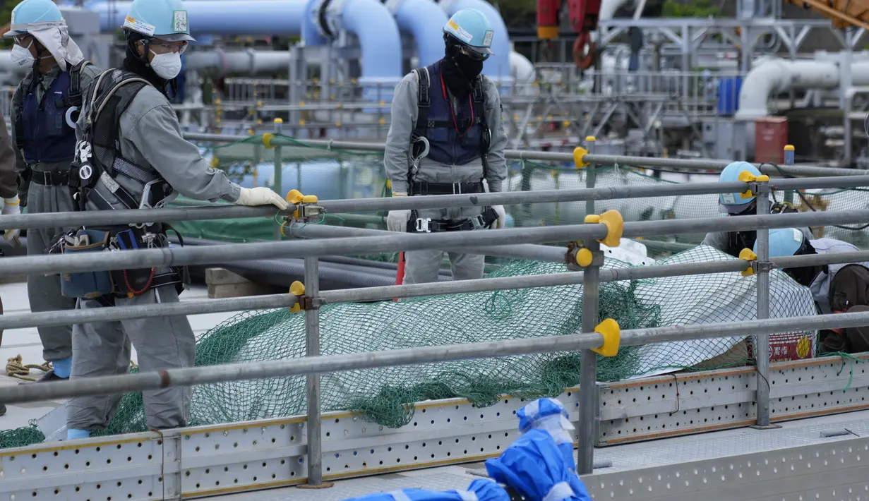 Para pekerja menyingkirkan bahan bangunan sebelum istirahat makan siang di pembangkit listrik tenaga nuklir Fukushima Daiichi, di kota Futaba, timur laut Jepang, Jumat, 14 Juli 2023. (AP Photo/Hiro Komae)