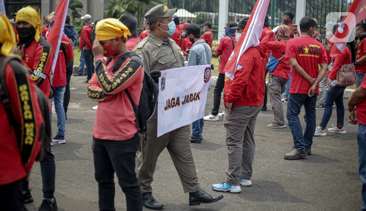Petugas Satpol PP memegang poster imbauan protokol kesehatan COVID-19 saat unjuk rasa buruh di depan Gedung DPR, Jakarta, Selasa (17/11/2020). Pemerintah terus mengingatkan pentingnya 3M yaitu memakai masker, menjaga jarak, dan mencuci sebagai upaya pencegahan Covid-19. (Liputan6.com/Faizal Fanani)