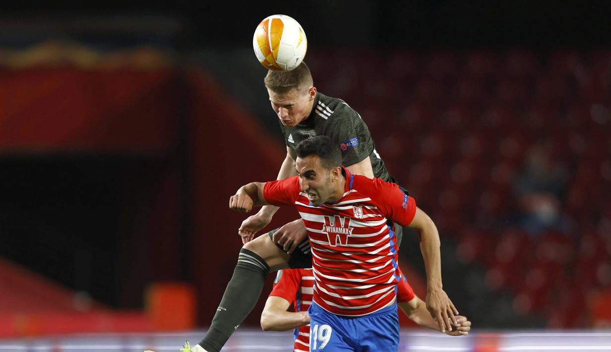 Gelandang Manchester United, Scott McTominay berduel udara dengan gelandang Granada, Angel Montoro dalam laga leg pertama perempatfinal Liga Europa 2020/2021 di Nuevo Los Carmenes Stadium, Granada, Kamis (8/4/2021). Manchester United menang 2-0 atas Granada. (AP/Fermin Rodriguez)