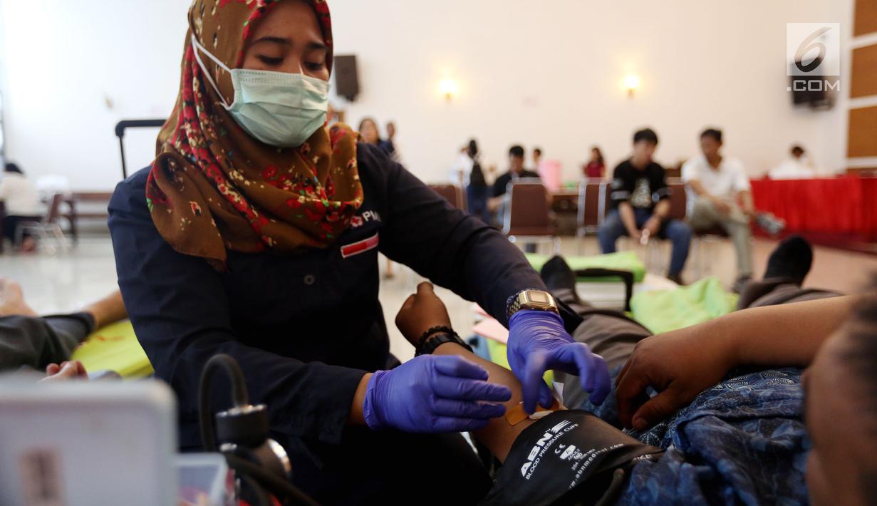 Petugas muslim dari Palang Merah Indonesia (PMI) membantu Jemaat Gereja Protestan Indonesia Bagian Barat (GPIB) dalam donor darah, Jakarta, Minggu (3/12). Kegiatan tersebut diadakan dalam rangkaian acara Natal. (Liputan6.com/JohanTallo)