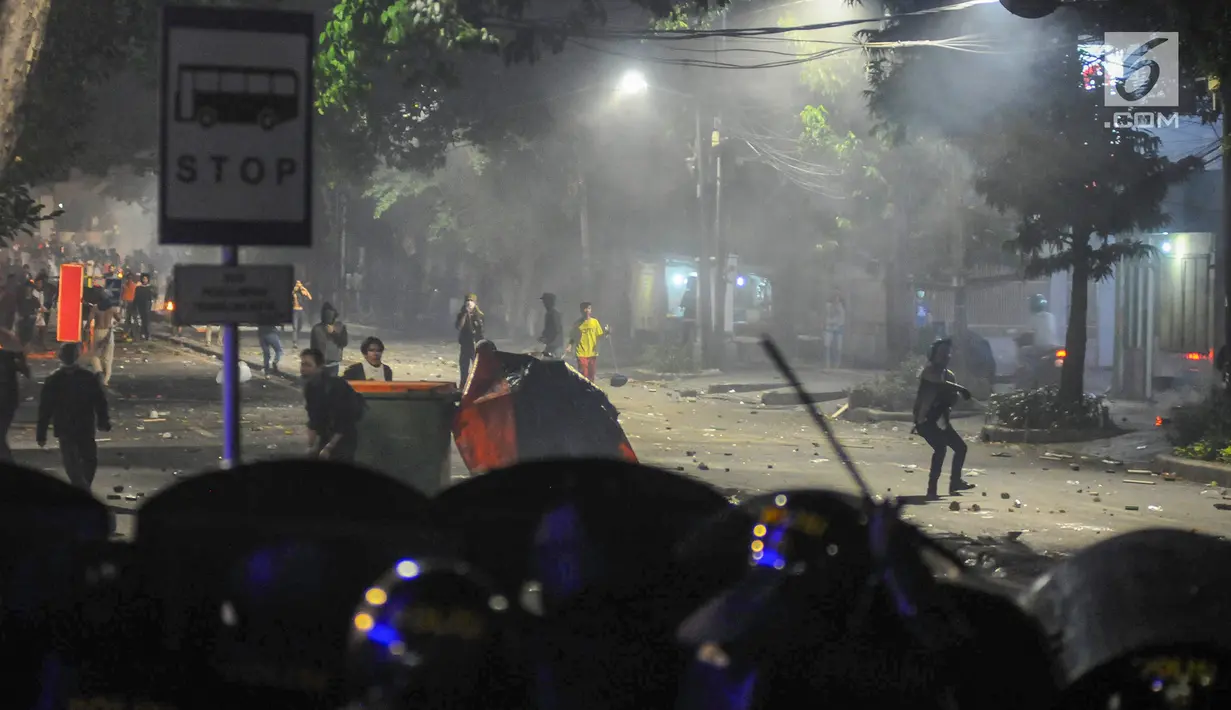 Massa aksi melempar benda ke arah barikade Polisi di kawasan Tanah Abang, Jakarta Pusat, Rabu (22/5/2019). Massa terus melakukan perlawanan meski polisi menembakkan gas air mata pasca buntut dari unjuk rasa di depan kantor Bawaslu. (Liputan6.com/Herman Zakharia)