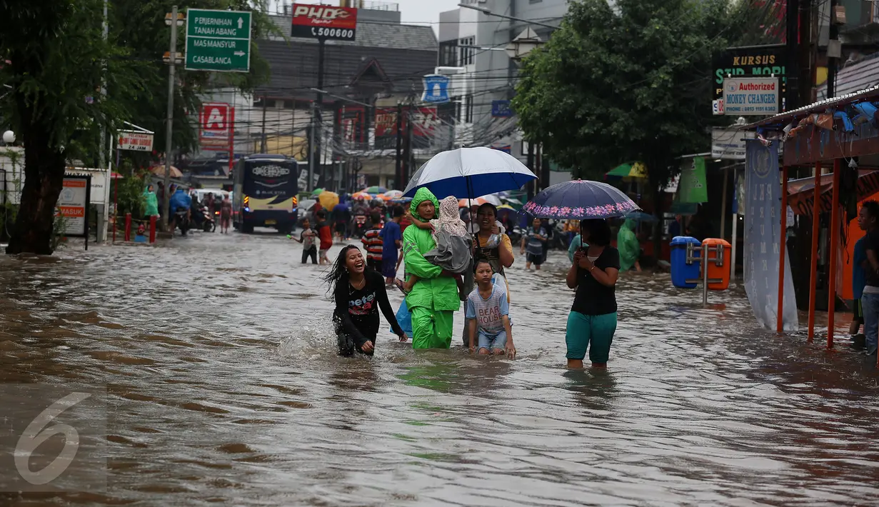 Warga bersama anak-anak melihat banjir yang merendam kawasan Benhil RT 03 RW 05, Jakarta Pusat, Selasa (21/1). Hujan deras yang mengguyur sejak Selasa dinihari mengakibatkan kawasan tersebut mengalami banjir. (Liputan6.com/Johan Tallo)