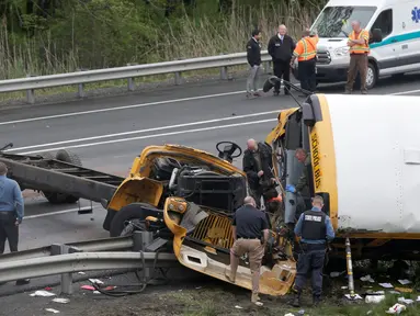 Personel darurat memeriksa kondisi bus sekolah yang bertabrakan dengan truk sampah di Interstate 80, Mount Olive, New Jersey, Kamis (17/5). Akibat kecelakaan itu, seorang siswa dan seorang guru tewas, serta lebih dari 40 orang terluka. (AP/Seth Wenig)