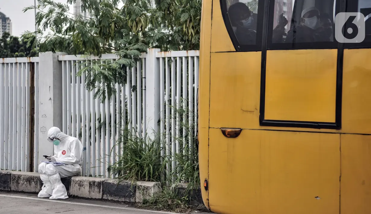 Petugas medis terduduk saat sejumlah pasien COVID-19 terlihat dalam bus sekolah yang tiba di RSD Wisma Atlet, Kemayoran, Jakarta, Selasa (17/11/2020). Jumlah pasien COVID-19 di RSD Wisma Atlet yang semula 1.580 orang kini menjadi 1.667 orang. (merdeka.com/Iqbal S. Nugroho)