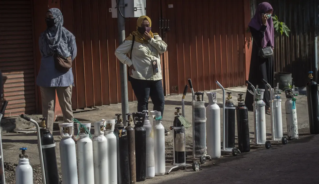 Warga mengantre untuk mengisi ulang tabung oksigen di stasiun pengisian di kota Surabaya, Kamis (15/7/2021). Di Surabaya, masih banyak permintaan isi ulang oksigen, baik tabung kecil 0,5–1 meter kubik hingga ukuran besar 6–7 meter kubik. (Juni Kriswanto / AFP)