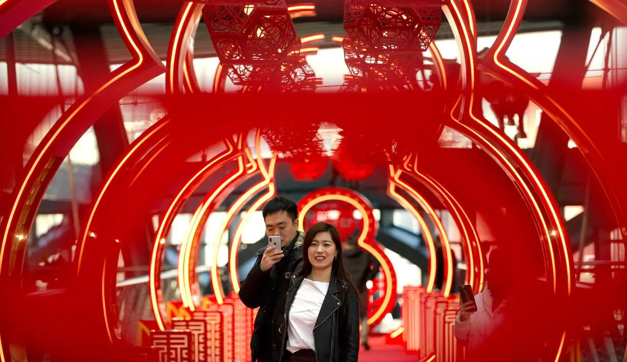 Pengunjung berfoto di sebuah jembatan bertema Imlek di sebuah pusat perbelanjaan kelas atas di Beijing (21/2). Saat perayaan Imlek, warga Tionghoa di China berkumpul dan makan makanan tradisional. (AP Photo / Mark Schiefelbein)
