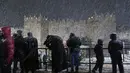 Orang-orang berjalan saat badai salju di sebelah Gerbang Damaskus di Kota Tua Yerusalem, Rabu (26/1/2022). Hujan salju yang jarang melanda sebagian wilayah Israel dan Tepi Barat, menutup sekolah dan bisnis. (AP Photo/Mahmoud Illean)