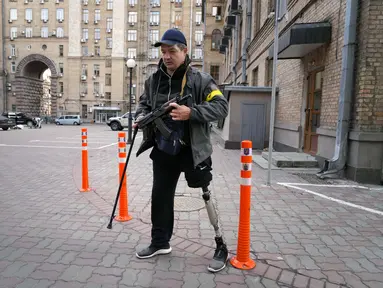 Seorang pria pertahanan sipil bersenjata berpatroli di jalan yang kosong karena jam malam di Kiev, Ukraina, Minggu (27/2/2022). Pihak berwenang Ukraina mengatakan bahwa pasukan Rusia telah memasuki kota terbesar kedua di Ukraina Kharkiv dan pertempuran di jalan-jalan. (AP Photo/Efrem Lukatsky)