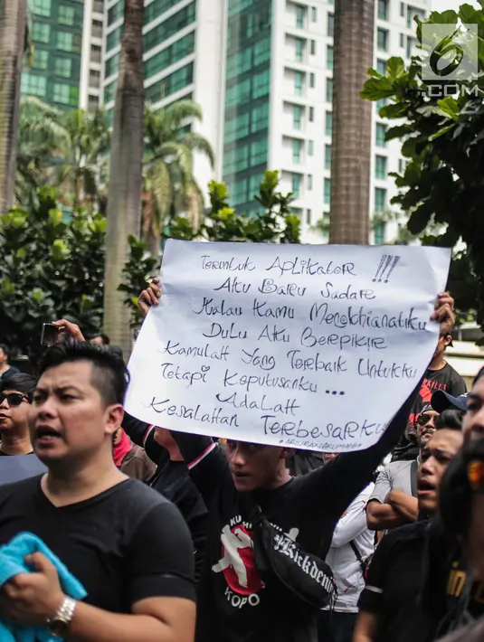 Pengemudi online membentangkan poster saat menggelar aksi di kantor pusat Grab, Jakarta, Senin (29/10). Mereka menuntut open suspen bagi mitra individu tanpa syarat, penentuan tarif dan skema yang manusiawi. (Liputan6.com/Faizal Fanani)