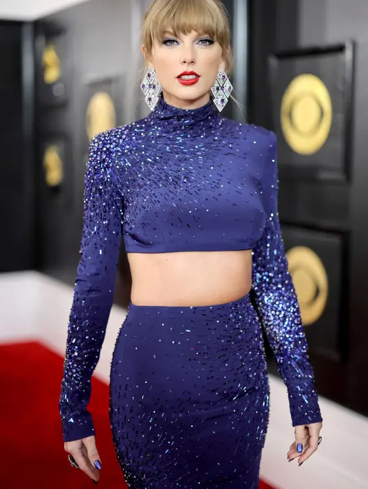 Taylor Swift saat berjalan di karpet merah ajang Grammy Awards 2023 di Crypto.com Arena, Los Angeles, AS, Senin (6/2/2023) pagi waktu Indonesia. Melansir dari ET Online, para penggemar pun dengan cepat menelusuri bahwa gaun tersebut  memiliki warna yang sama dengan gaun GRAMMY era Fearless-nya dan seperti penampilan GRAMMY 1989-nya, itu adalah pakaian dua potong (two-piece). (Neilson Barnard / Getty Images via AFP))