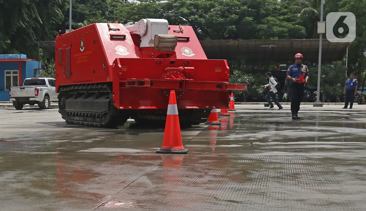 Petugas pemadam kebakaran mengoperasikan robot damkar jenis Dok-INK MVF- U3 di kantor PKP DKI Jakarta, Kamis (13/2/2020). Robot yang besarnya berkisar 3x4 meter dan digerakkan dengan remote control ini memiliki kapasitas volume air 2.500 liter dan foam 500 liter. (Liputan6.com/Herman Zakharia)