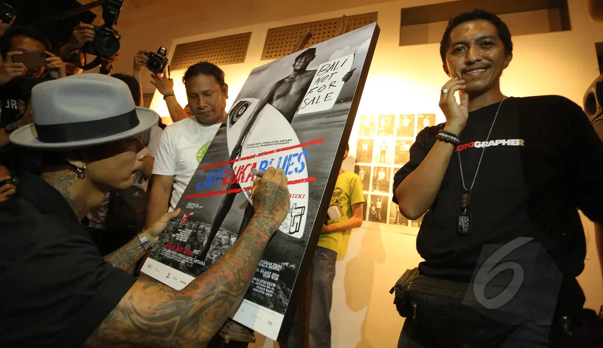 Drummer grup musik Superman Is Dead, Jrx (kiri) menandatangani foto saat pameran fotografi "Laut Luka Blues" di Galeri Foto Jurnalistik Antara , Jakarta, Jumat (22/5/2015). 51 karya foto karya Ismar Patrizki dipamerkan. (Liputan6.com/Faizal Fanani)