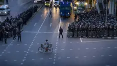 Seorang pria mengendarai sepedanya melewati polisi antihuru-hara yang mengambil posisi di persimpangan menuju Gedung Pemerintah setelah mengejar sekelompok kecil demonstran pro-demokrasi di Bangkok, Thailand, Kamis (15/10/2020). (AP Photo/Gemunu Amarasinghe)
