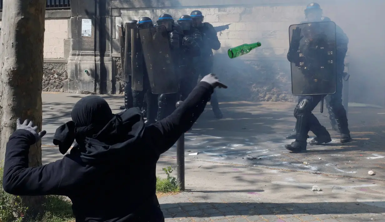 Seorang pemuda melempar botol ke arah polisi anti huru-hara ketika aksi protes rancangan UU ketenagakerjaan Prancis selama peringatan May Day 2016 atau Hari Buruh Sedunia di Paris , Minggu (1/5). (REUTERS/Philippe Wojazer)