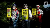 Angggota Komunitas Aku Badut Indonesia (ABI) melakukan aksi kampanye penggunaan di kawasan Cilandak, Jakarta Selatan, Senin (12/7/2021). Selain itu, mereka juga membagi-bagikan masker secara gratis bagi para pengendara motor yang melintas. (Liputan6.com/Johan Tallo)