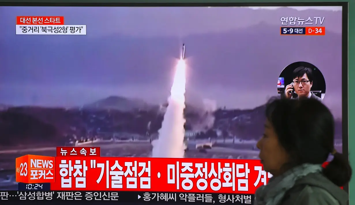 Seorang wanita melewati layar televisi yang menyiarkan berita peluncuran rudal oleh Korea Utara (Korut), di sebuah stasiun kereta di Seoul, Korea Selatan, Selasa (5/4). Rudal itu ditembakkan dari wilayah timur Korut ke arah Laut Jepang. (JUNG Yeon-Je/AFP)