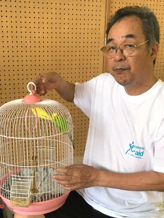 Pengungsi Akira Tanimoto menunjukkan burung parkit peliharaannya di pusat evakuasi di Hiroshima, Jepang, Selasa (10/7). (AP Photo/Haruka Nuga)