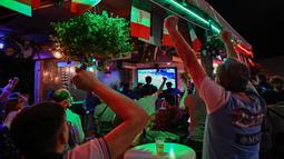 Fans bersorak setelah timnas Italia membuka skor, saat mereka menonton di sebuah bar di Roma pada laga pertama grup A Euro 2020 /2021, Jumat (11/6/2021). Timnas Italia berhasil menang 3-0 atas Turki. (ANDREAS SOLARO/AFP)