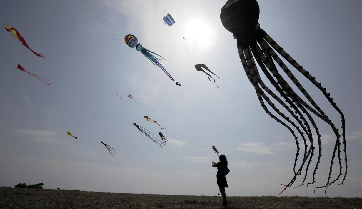 Seorang wanita melihat layang-layang dalam Varvara Kite Fest di Desa Varvara, pesisir Laut Hitam, Bulgaria, Jumat (27/8/2021). Penyelenggara Varvara Kite Fest Andrey Kulev mengatakan bahwa menerbangkan layang-layang seperti melepaskan semua masalah Anda di langit. (AP Photo/Valentina Petrova)